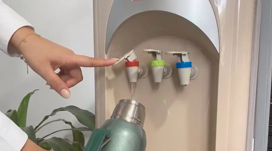 Mano sirviendo agua del dispenser Blue Star Water en un termo para el mate